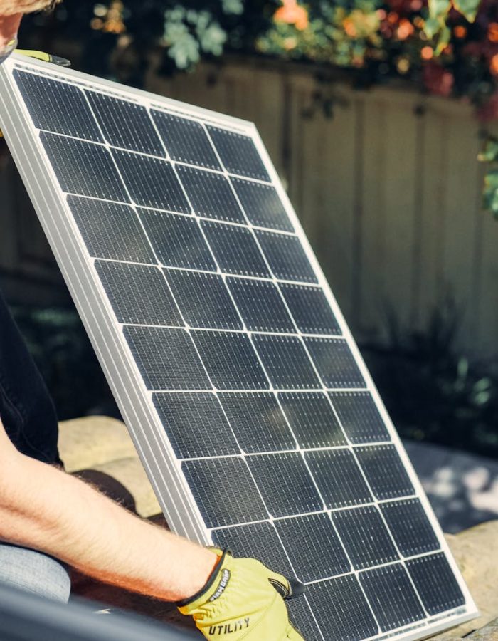 pexels-photo-9875410-9875410 A worker installs a solar panel in a garden, promoting clean energy.